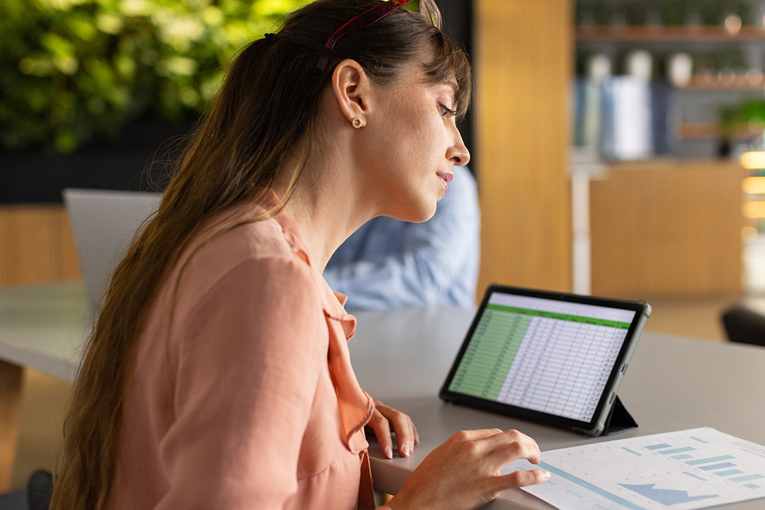 Analyzing data on tablet, woman working in modern office environment. Technology, business, professional, digital, workplace, productivity
